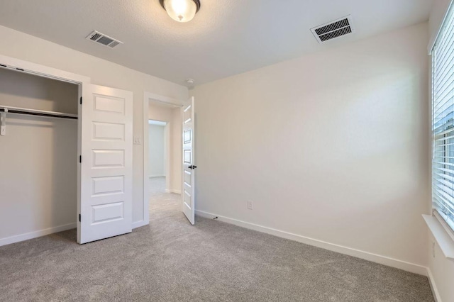 unfurnished bedroom featuring light carpet, visible vents, and baseboards