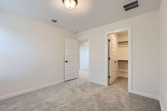 unfurnished bedroom with carpet, a spacious closet, and visible vents