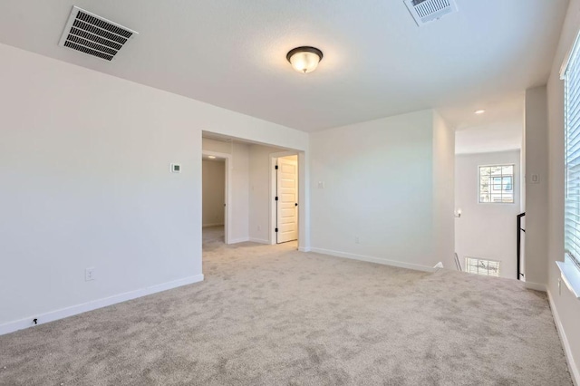 unfurnished room with light carpet, visible vents, and baseboards