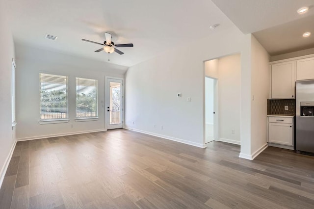 unfurnished living room with dark wood-style flooring, visible vents, and baseboards