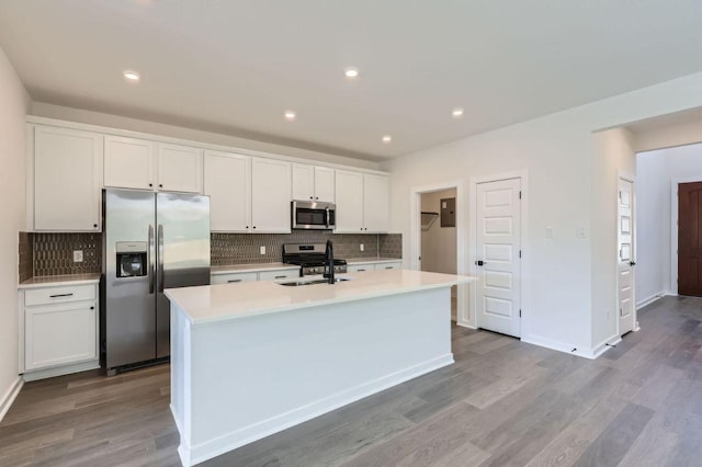 kitchen featuring an island with sink, appliances with stainless steel finishes, light countertops, white cabinetry, and a sink