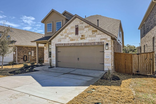 view of front of house featuring stone siding, an attached garage, fence, and driveway