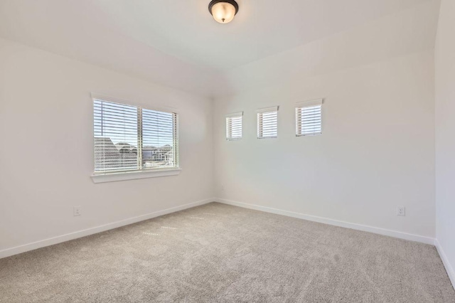 spare room with light colored carpet and baseboards