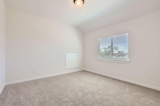 spare room featuring vaulted ceiling, baseboards, and carpet floors