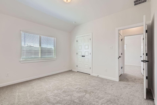 unfurnished bedroom featuring lofted ceiling, carpet, visible vents, and baseboards