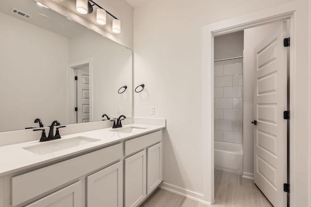 full bath featuring a sink, visible vents, baseboards, and double vanity