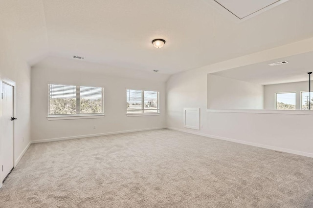 carpeted empty room with attic access, baseboards, and visible vents