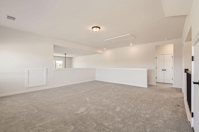 unfurnished room with visible vents, baseboards, carpet, and attic access