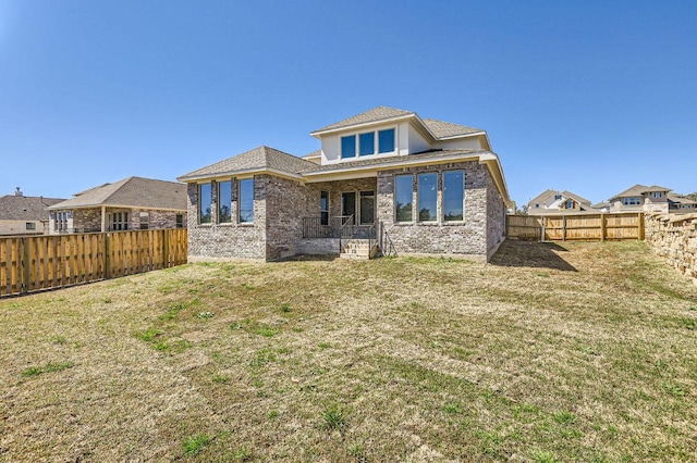 rear view of house featuring brick siding, a yard, and a fenced backyard