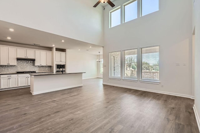 kitchen with ceiling fan, dark countertops, open floor plan, and dark wood finished floors