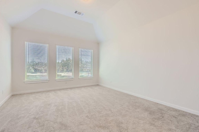 carpeted spare room featuring visible vents, baseboards, and vaulted ceiling