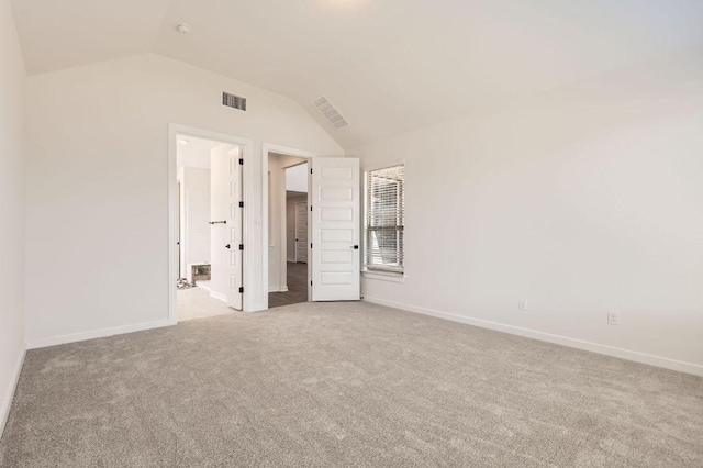 carpeted spare room with visible vents, baseboards, and vaulted ceiling