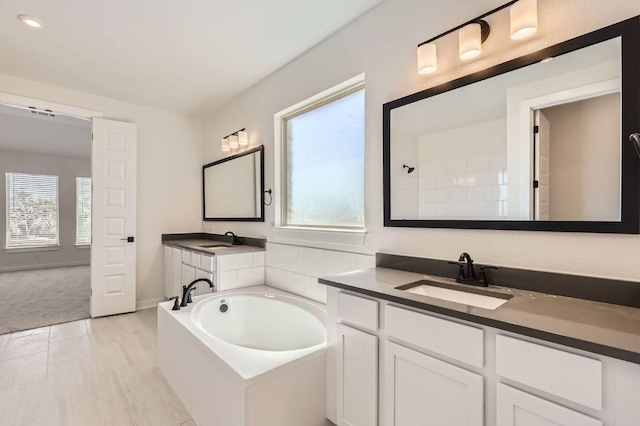 bathroom featuring a sink, two vanities, walk in shower, and a bath