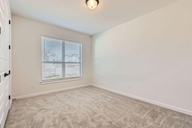 spare room with baseboards and light carpet