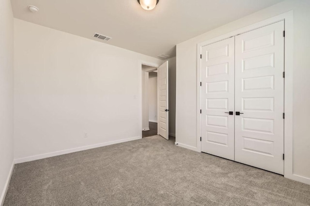 unfurnished bedroom with carpet, visible vents, a closet, and baseboards