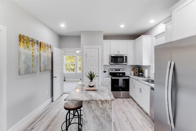 kitchen featuring a center island, light wood-type flooring, appliances with stainless steel finishes, and white cabinets