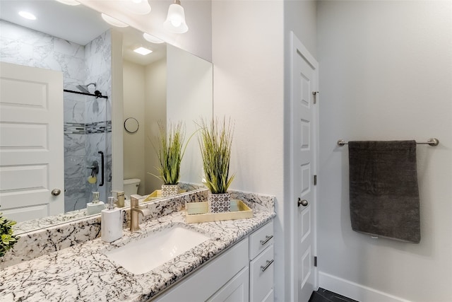 bathroom with toilet, an enclosed shower, and vanity