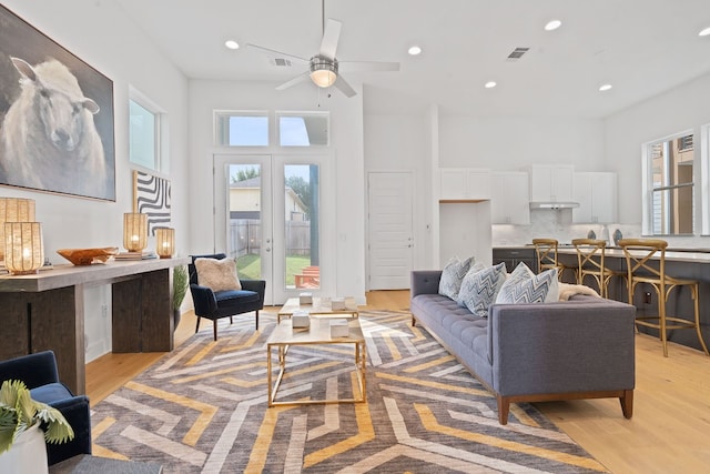 living room featuring ceiling fan, light hardwood / wood-style flooring, and french doors