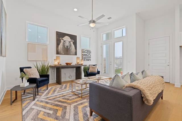 living room featuring ceiling fan, plenty of natural light, light hardwood / wood-style floors, and french doors