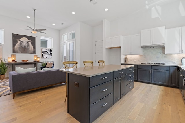 kitchen featuring white cabinets, a kitchen breakfast bar, a center island, and stainless steel gas stovetop