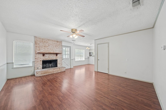 unfurnished living room with ceiling fan, a fireplace, dark hardwood / wood-style flooring, and a textured ceiling