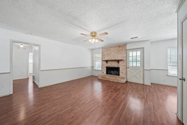 unfurnished living room with a fireplace, dark wood-type flooring, a textured ceiling, and ceiling fan