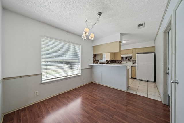 kitchen featuring a textured ceiling, light hardwood / wood-style flooring, kitchen peninsula, and white appliances