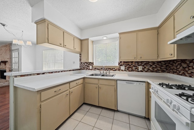 kitchen with white appliances, a textured ceiling, light tile patterned floors, kitchen peninsula, and sink