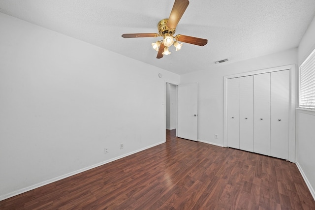 unfurnished bedroom featuring a textured ceiling, ceiling fan, dark hardwood / wood-style floors, and a closet