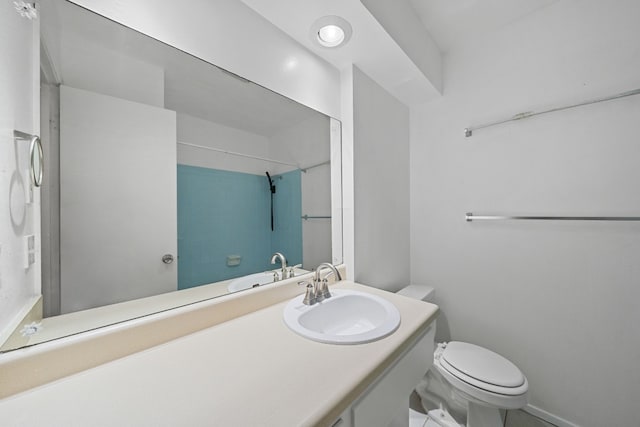 bathroom with tiled shower, vanity, and toilet