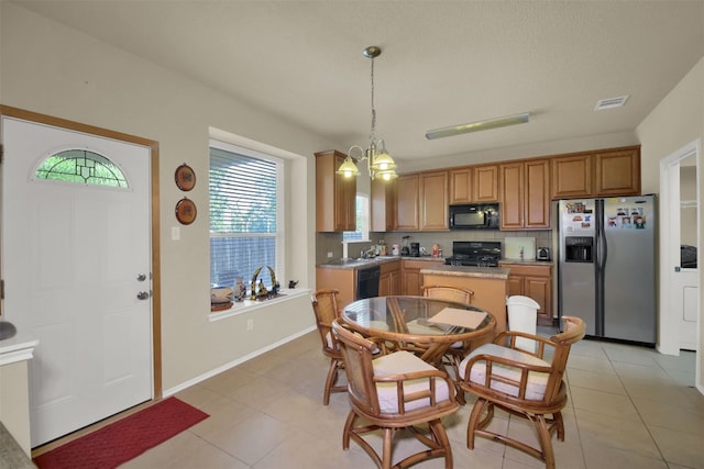 kitchen featuring light tile patterned flooring, hanging light fixtures, backsplash, black appliances, and a notable chandelier