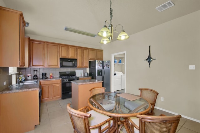 kitchen featuring decorative backsplash, black appliances, an inviting chandelier, a center island, and washer and clothes dryer