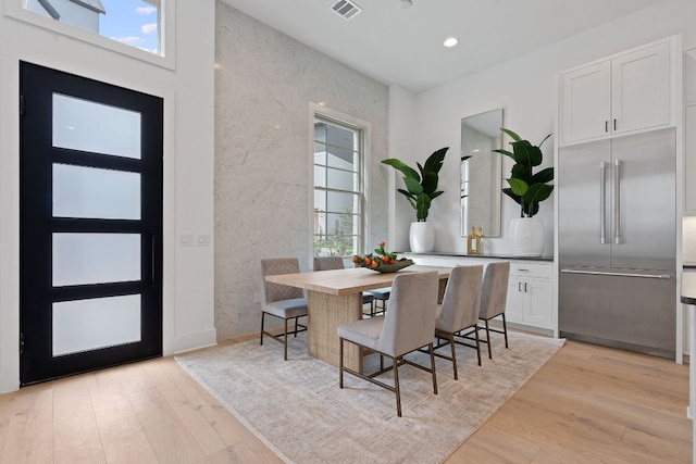 dining area with tile walls, light hardwood / wood-style flooring, and a wealth of natural light