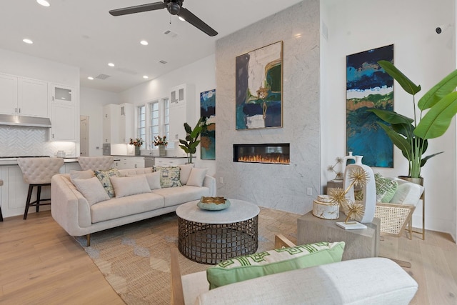 living room with light hardwood / wood-style floors, a fireplace, and ceiling fan