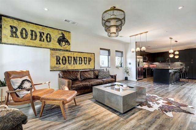 living room with hardwood / wood-style flooring, an inviting chandelier, and sink