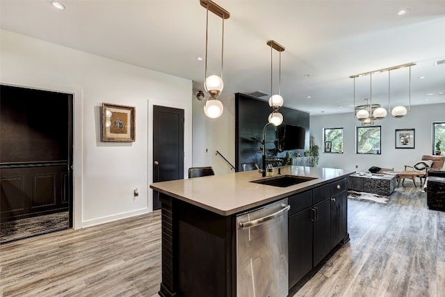 kitchen featuring a kitchen island with sink, light hardwood / wood-style flooring, decorative light fixtures, dishwasher, and sink