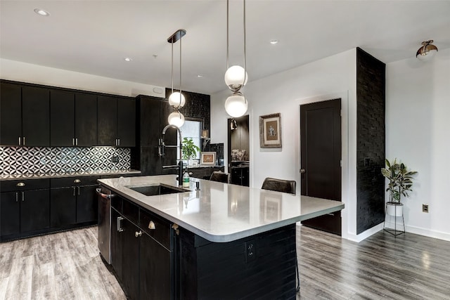 kitchen featuring a large island, decorative light fixtures, sink, a breakfast bar, and light hardwood / wood-style floors