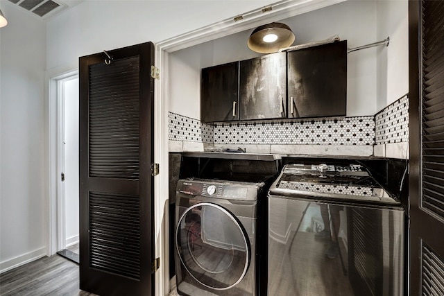 laundry room featuring dark wood-type flooring, cabinets, and washing machine and clothes dryer