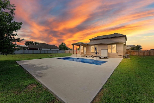 pool at dusk with a lawn and a patio