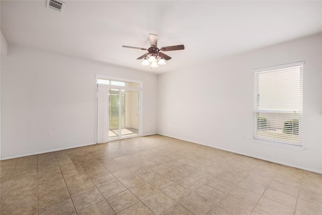 spare room featuring a ceiling fan, visible vents, a wealth of natural light, and baseboards