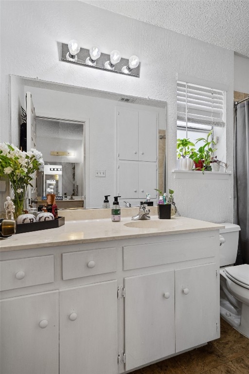 bathroom with vanity, a textured ceiling, toilet, and walk in shower