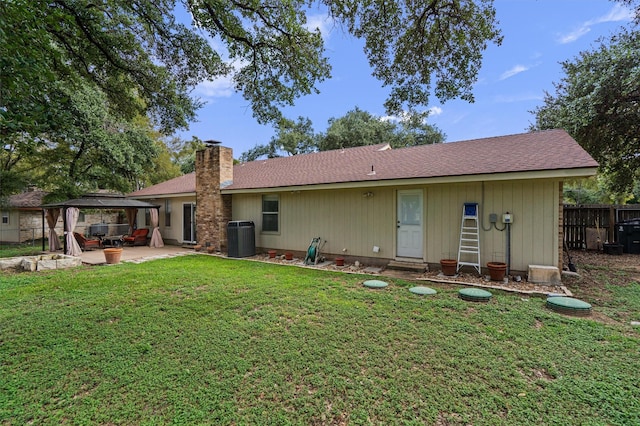 rear view of property featuring a yard, a gazebo, and central AC