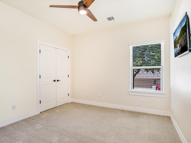 carpeted spare room with ceiling fan