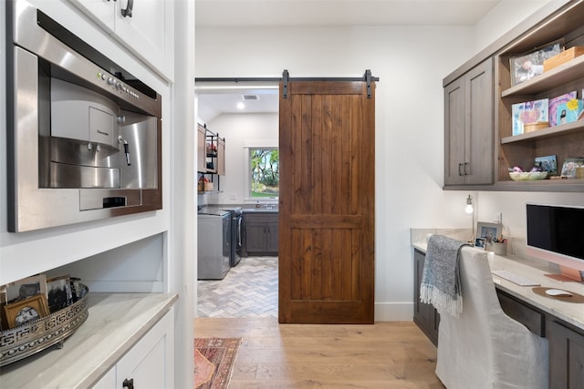 home office featuring a barn door and light hardwood / wood-style floors