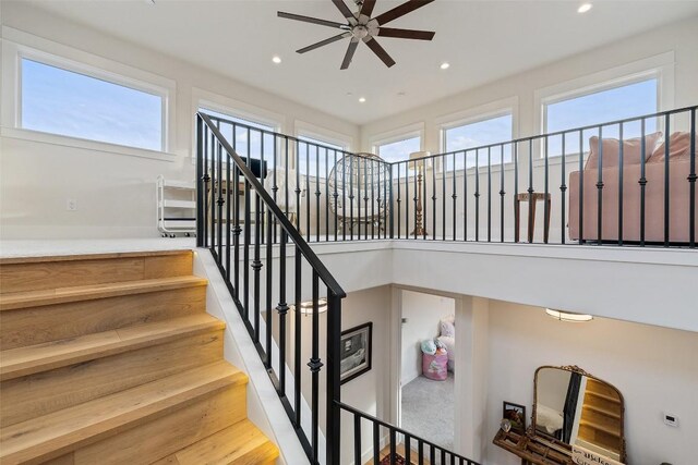 staircase featuring a wealth of natural light, ceiling fan, and hardwood / wood-style floors