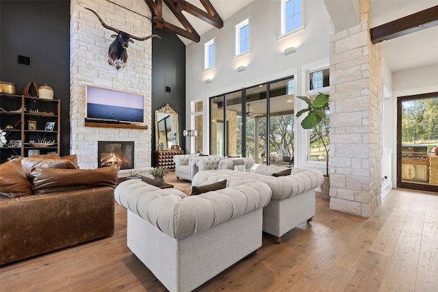 living room with high vaulted ceiling, wood-type flooring, a fireplace, and beamed ceiling