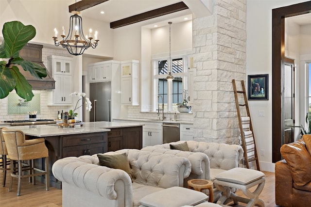 kitchen featuring pendant lighting, beam ceiling, stainless steel dishwasher, a wealth of natural light, and white cabinets