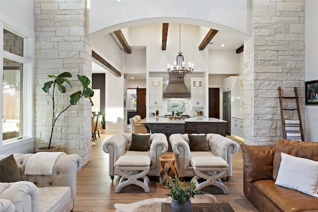 living room featuring light wood-type flooring, beamed ceiling, and a notable chandelier