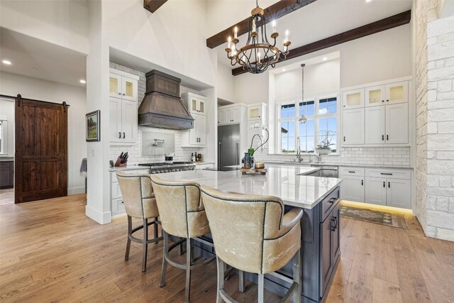 kitchen with a barn door, white cabinets, a large island, and light hardwood / wood-style floors