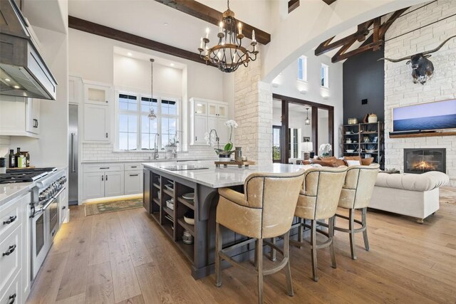 kitchen with decorative light fixtures, premium appliances, white cabinetry, and a stone fireplace